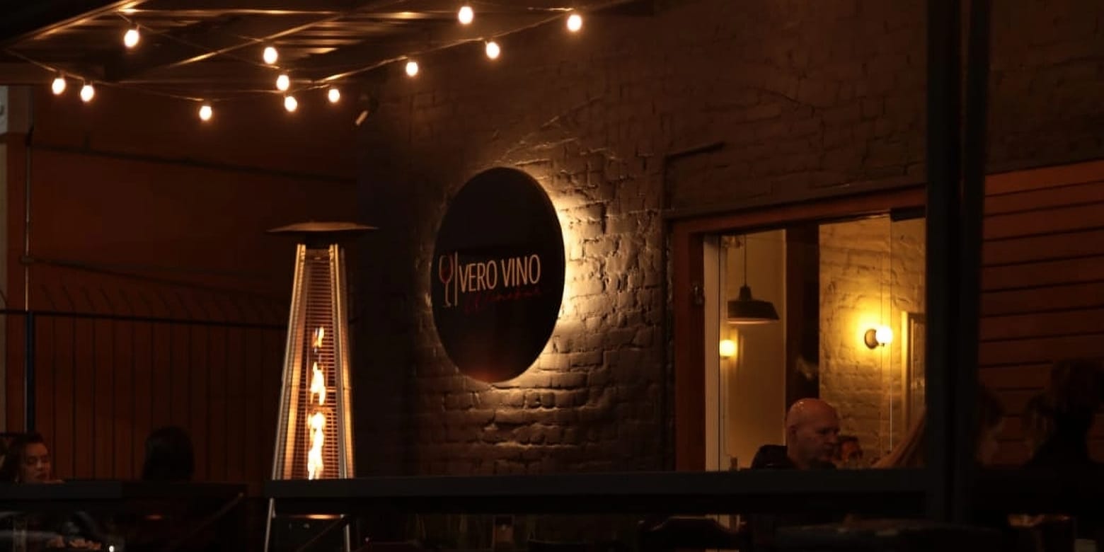 Salão do Vero Vino à noite, com letreiro aceso e luzes quentes