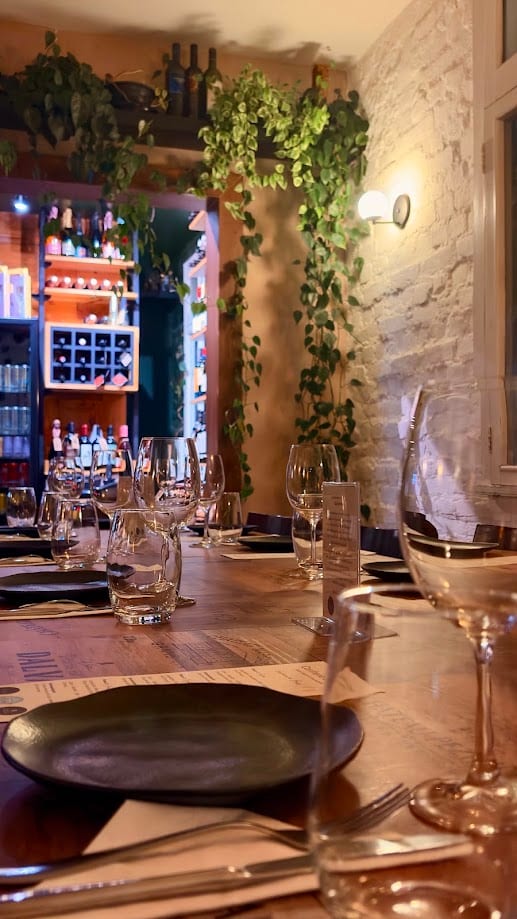 Mesa posta do winebar, com taças e parede verde ao fundo